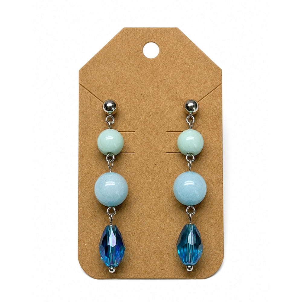 A pair of drop earrings displayed on a brown kraft card. Each earring has three stacked round beads in pale mint green, light blue, and deep blue, finished with a faceted blue teardrop bead at the bottom and silver-tone posts.
